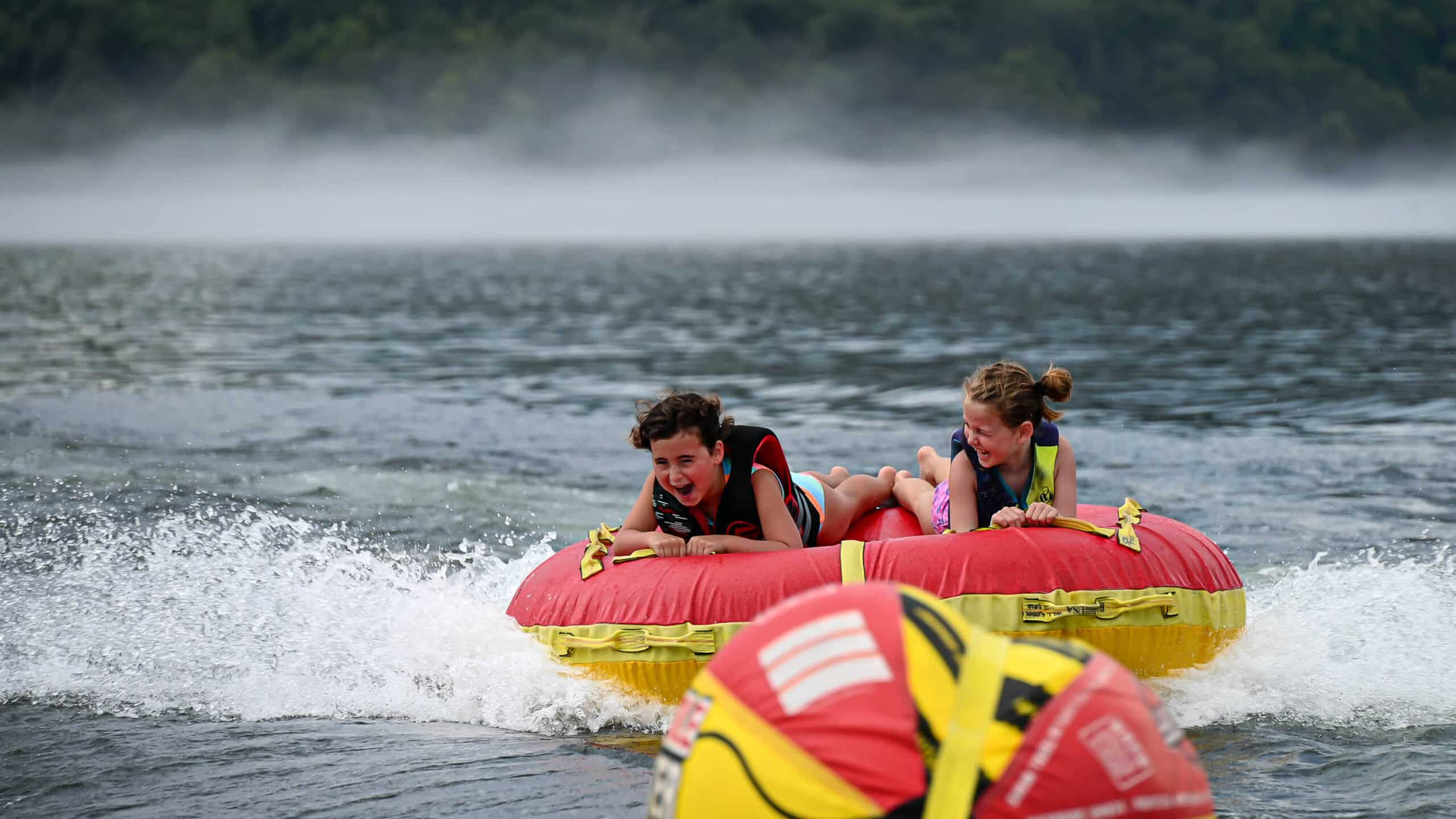 Two Kampers riding a tube across the lake at Kanakuk